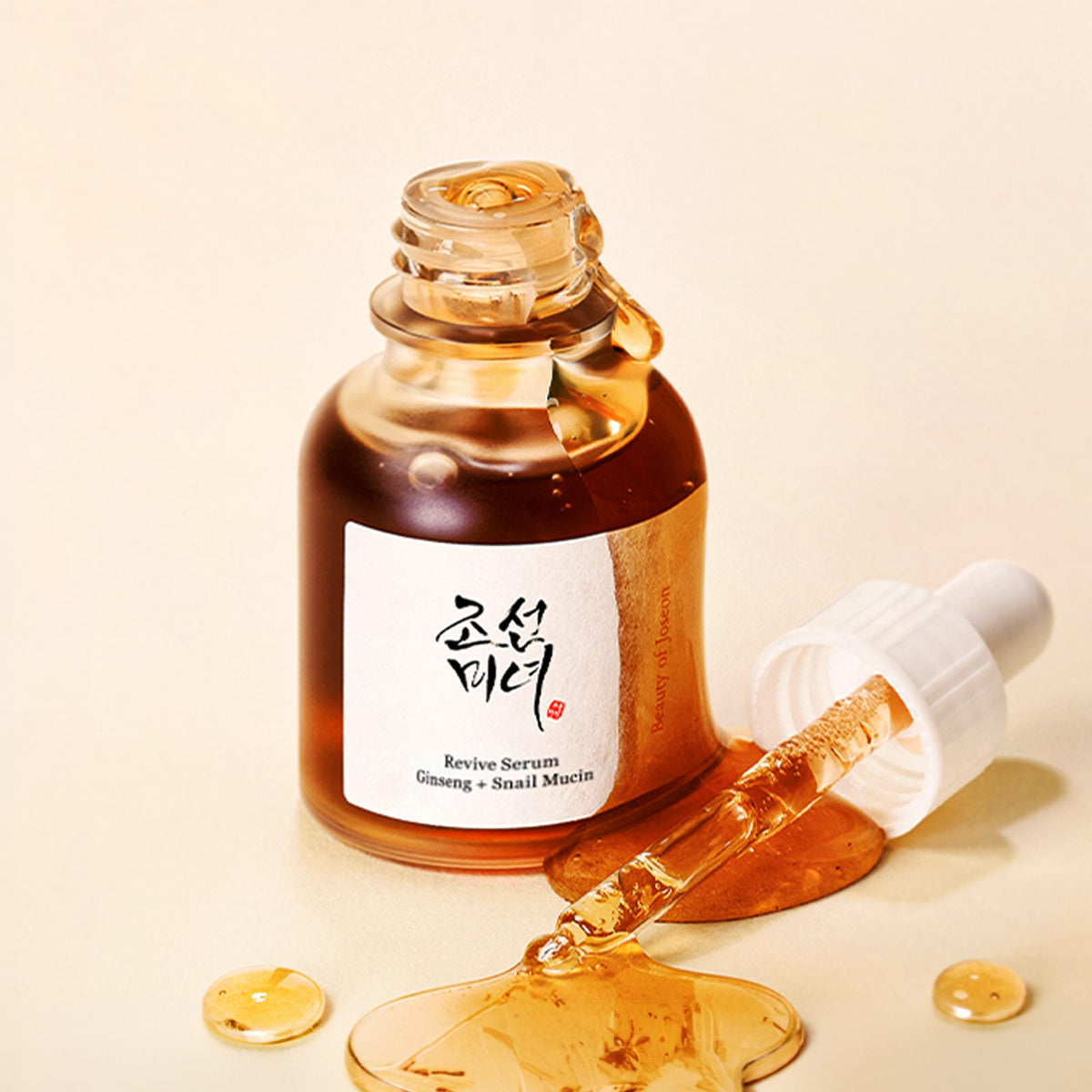 Flacon de sérum Beauty of Joseon au ginseng ouvert, pipette et texture ambrée sur fond pêche