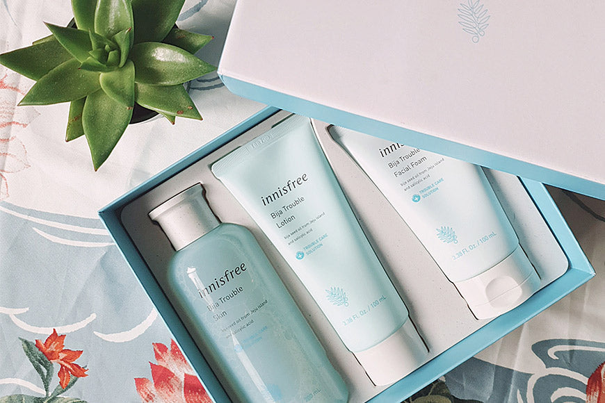 Coffret de soins INNISFREE: BIJA TROUBLE avec produits de beauté sur une table décorée.