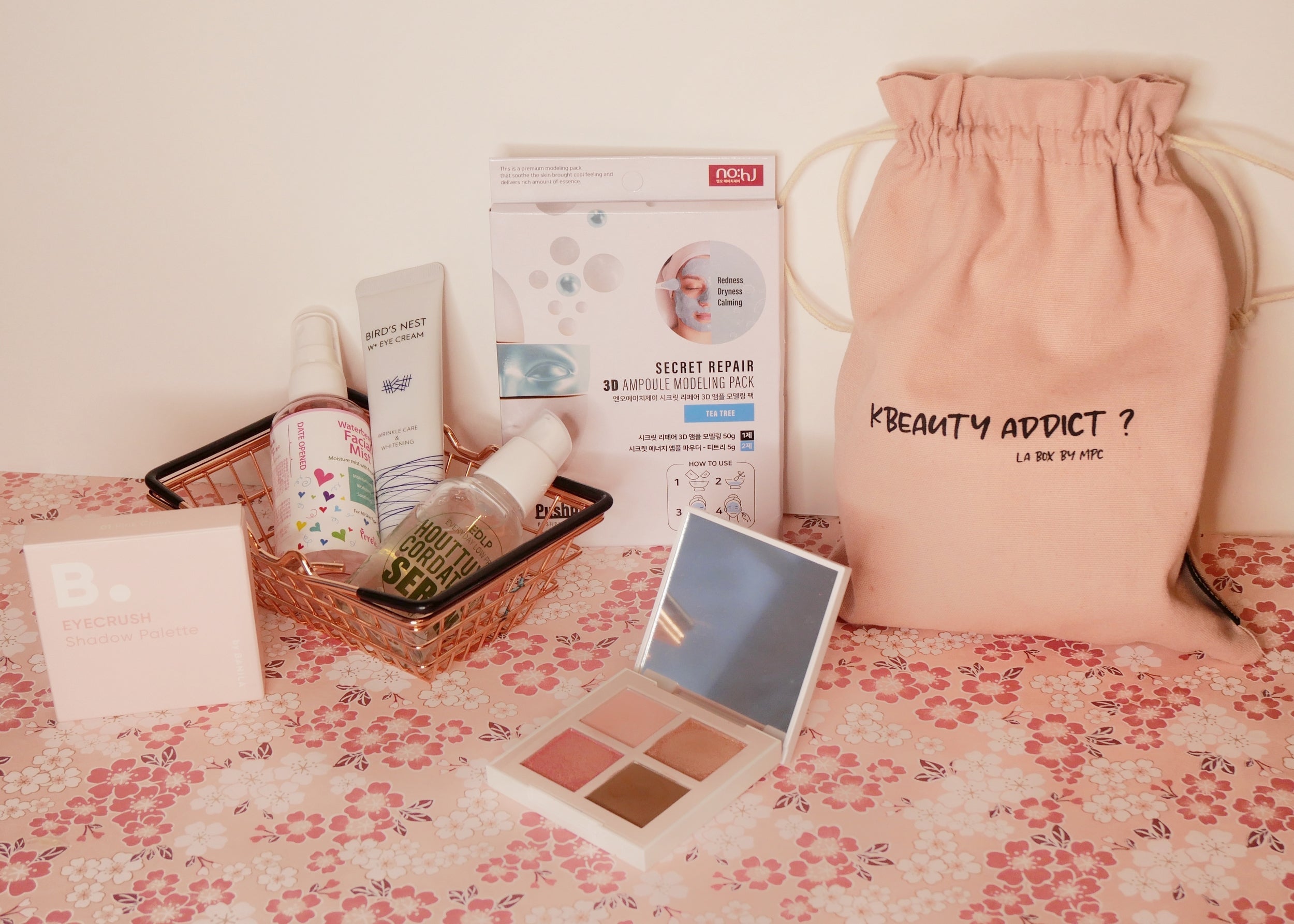Contenu de la KBeauty Box Février 2022 avec cosmétiques et maquillage doux sur fond floral