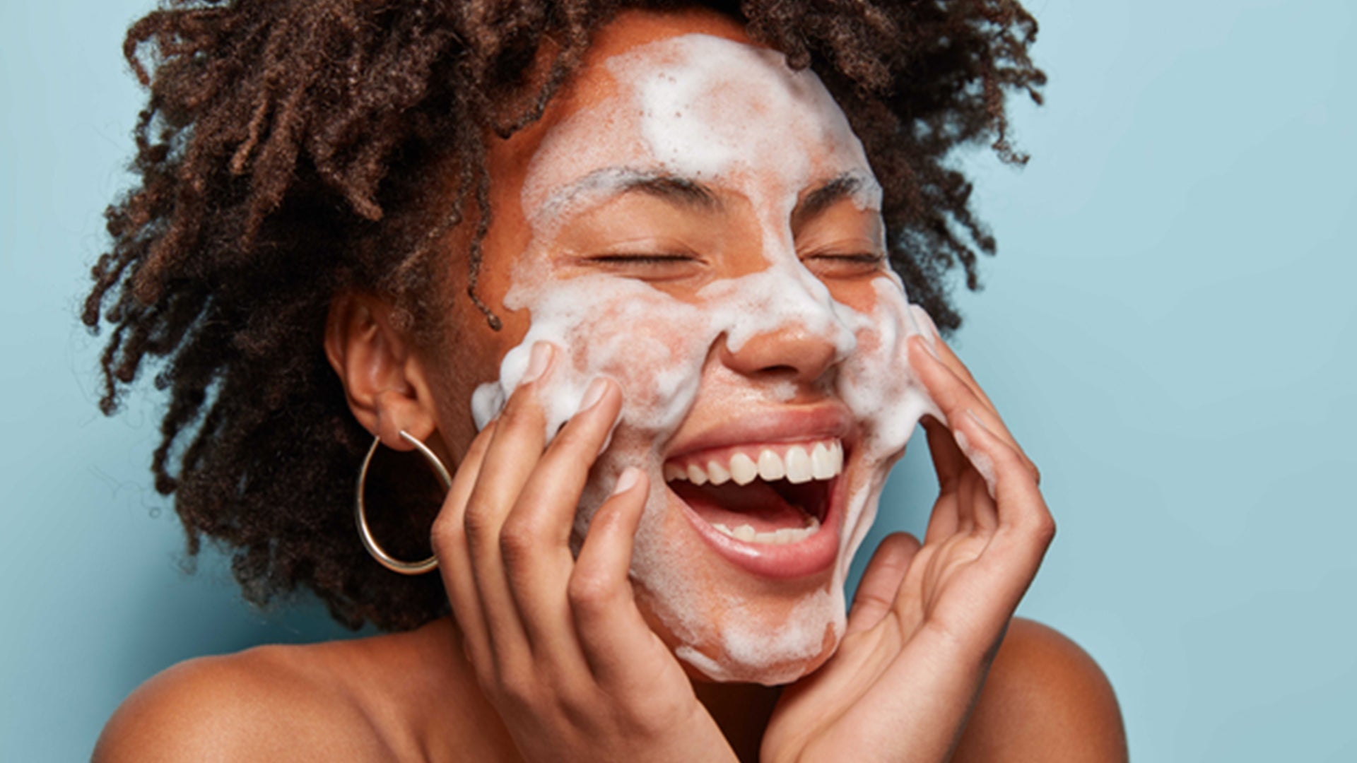 Femme souriante appliquant de la mousse pour le Guide du Débutant pour le Double Nettoyage Coréen.