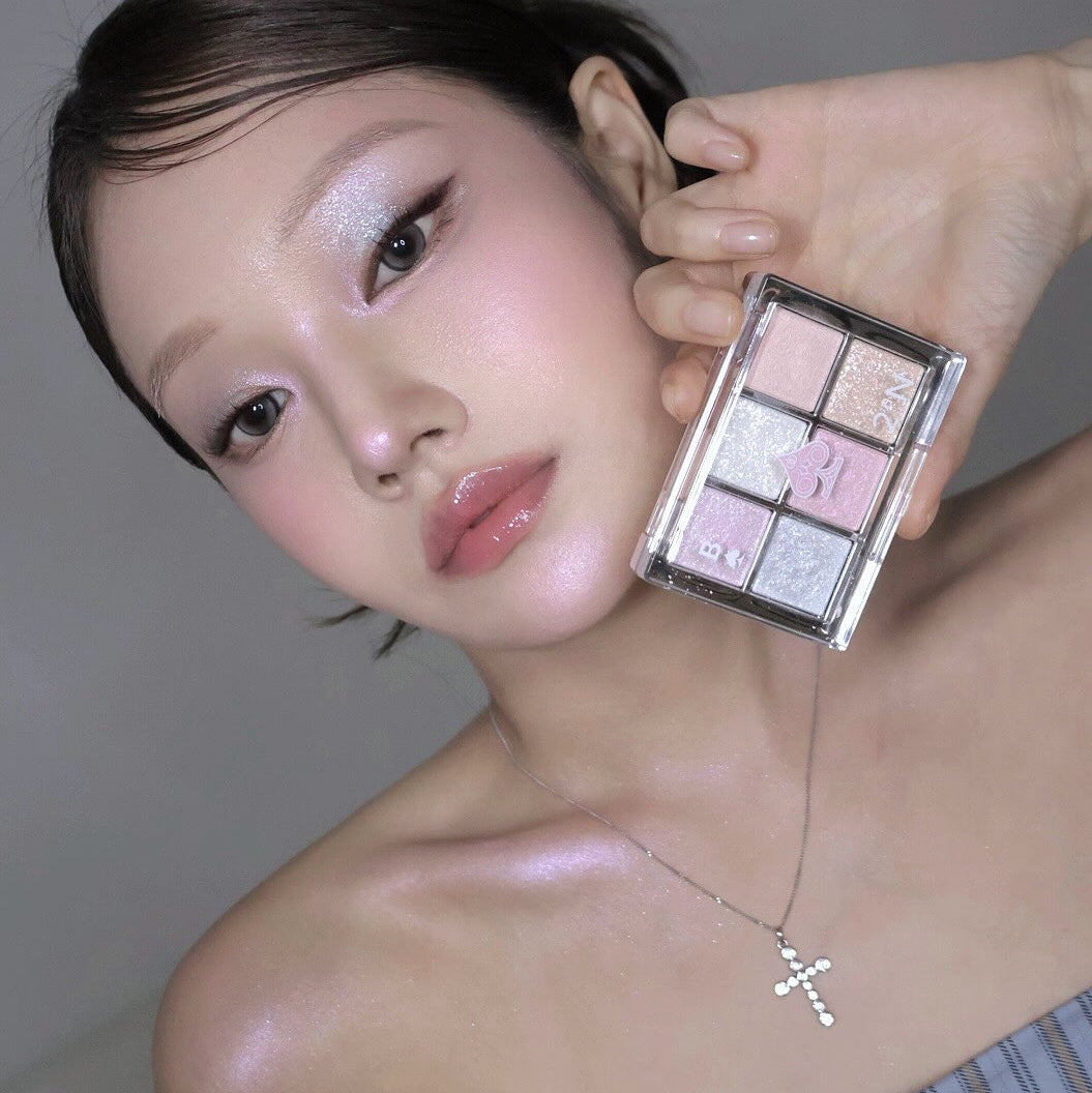 2AN Better Me Eye Palette 4.5g, maquillage yeux sur modèle, palette ouverte avec fards rose et violets, fond gris.