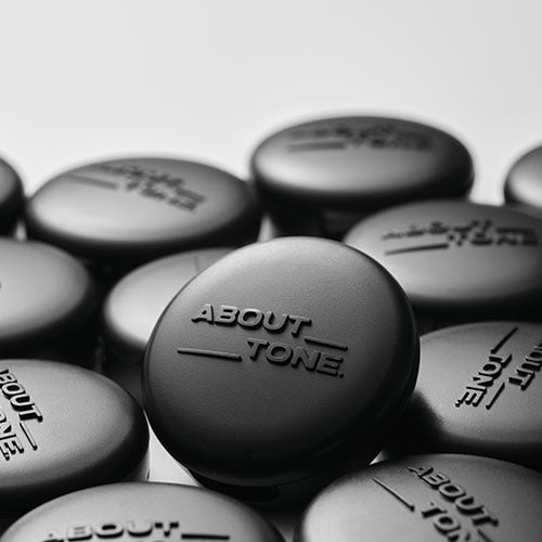ABOUT TONE Blur Powder Pact, boîtiers noirs flous sur fond clair, gros plan beauté, marque en évidence.