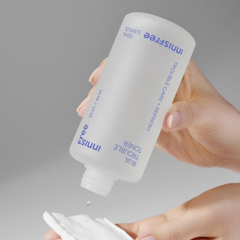 INNISFREE Bija Trouble Toner 170ml de la marque Innisfree, main versant une lotion sur peau, fond gris.