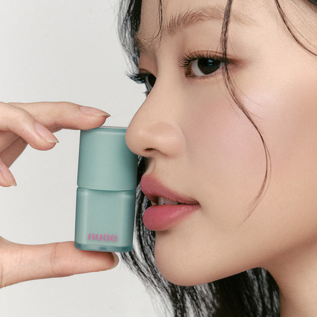 NUSE Mousse Liptual : femme appliquant la mousse à lèvres NUSE, gros plan sur un flacon bleu en studio clair.