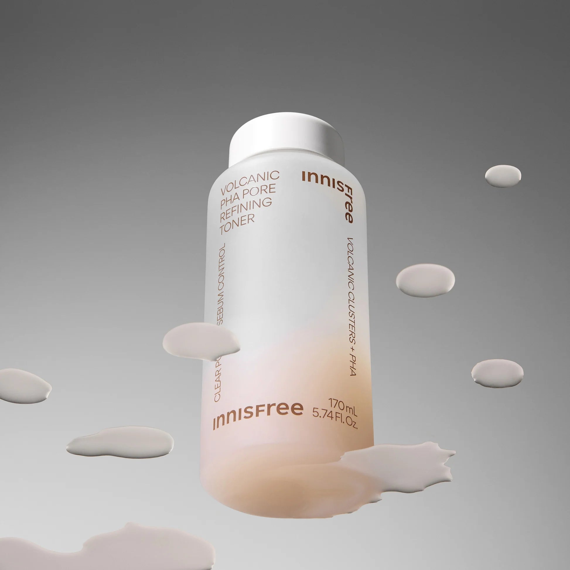 INNISFREE Volcanic PHA Pore Refining Toner 170ml, flacon en studio avec fond gris et éclaboussures blanches.