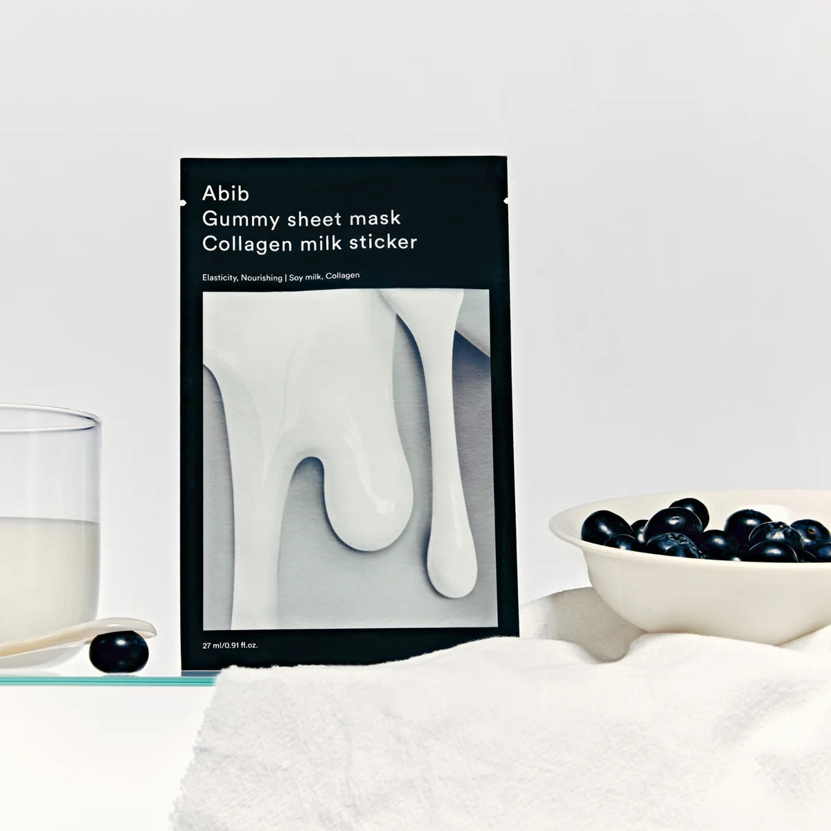 ABIB Gummy Sheets Mask Collagen Milk Sticker de la marque ABIB, photo sur table avec flacon de lait et grains bleus