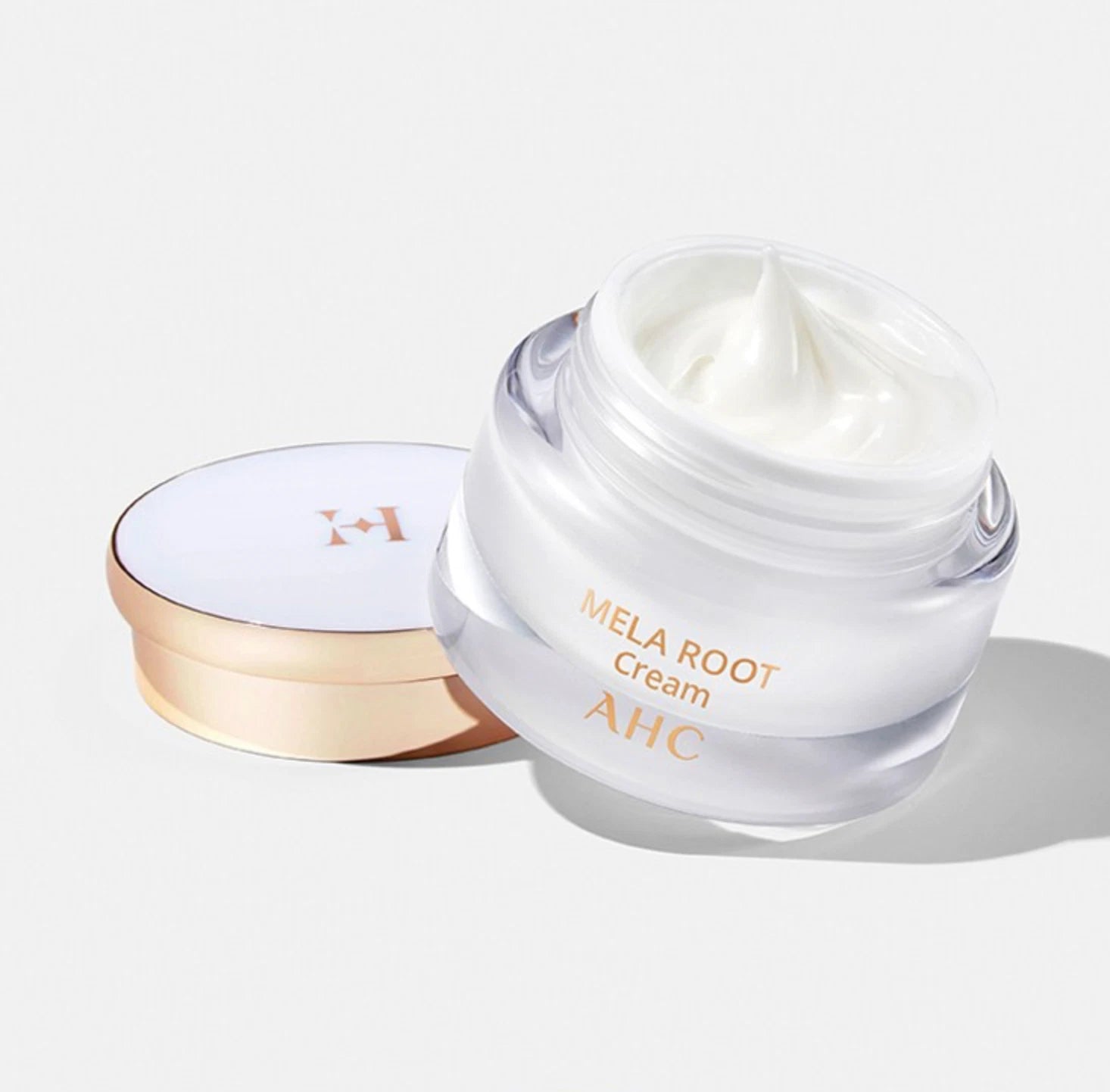 AHC H Mela Root Cream 50ml, crème éclaircissante AHC, pot ouvert avec texture blanche sur fond clair, studio