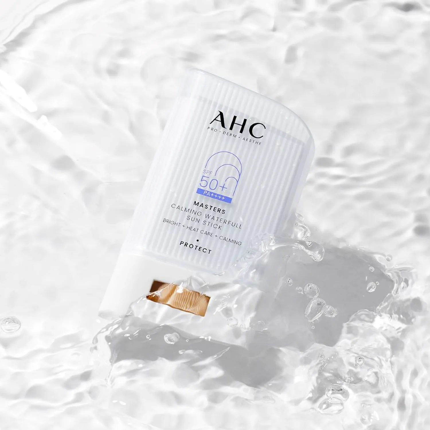 AHC Masters Calming Waterfull Sun Stick 22g AHC, stick solaire apaisant sur fond blanc avec bulles d’eau, contexte visuel produit.