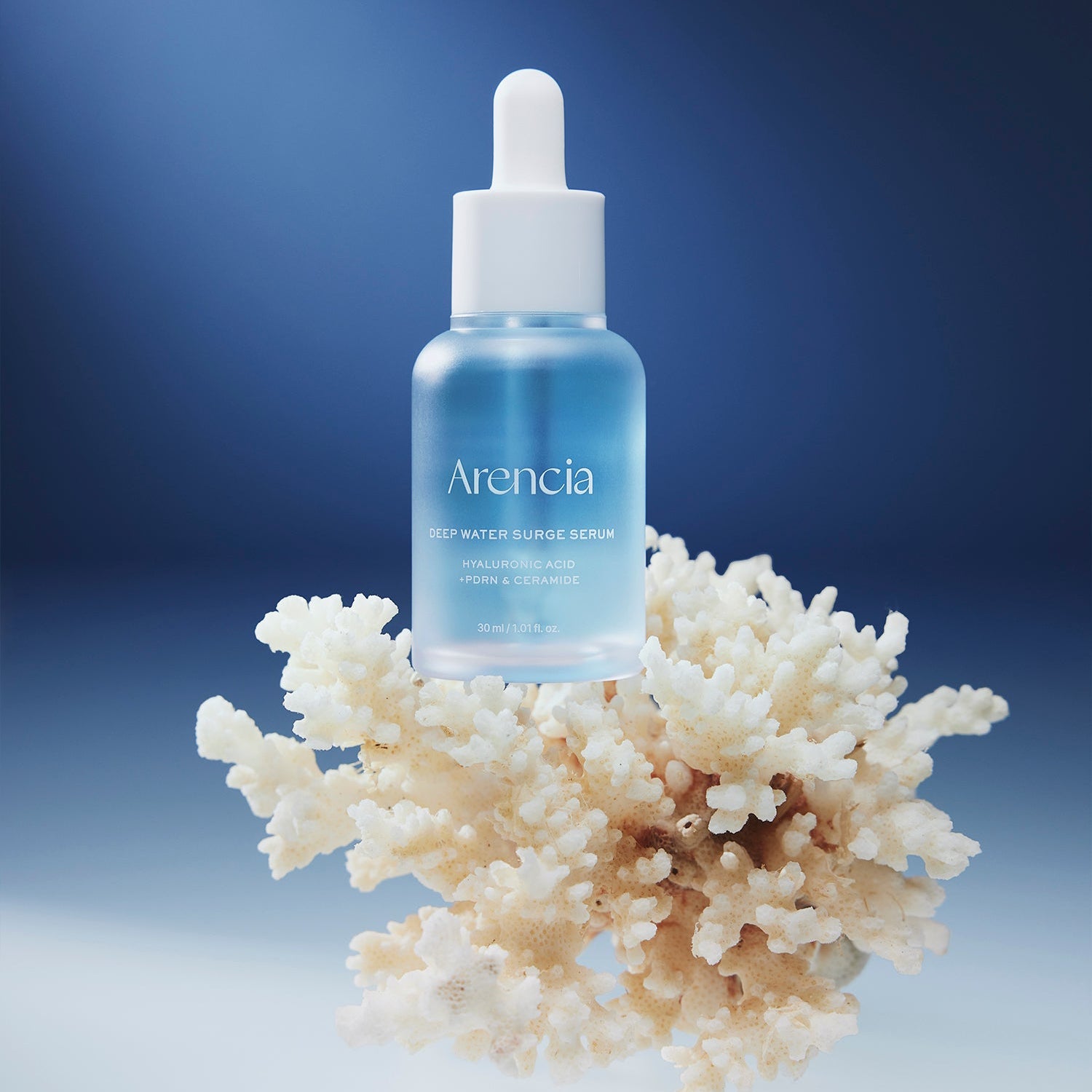 ARENCIA Deep Water Surge Serum 30ml sur fond bleu avec fleurs blanches, bouteille de la marque ARENCIA en gros plan