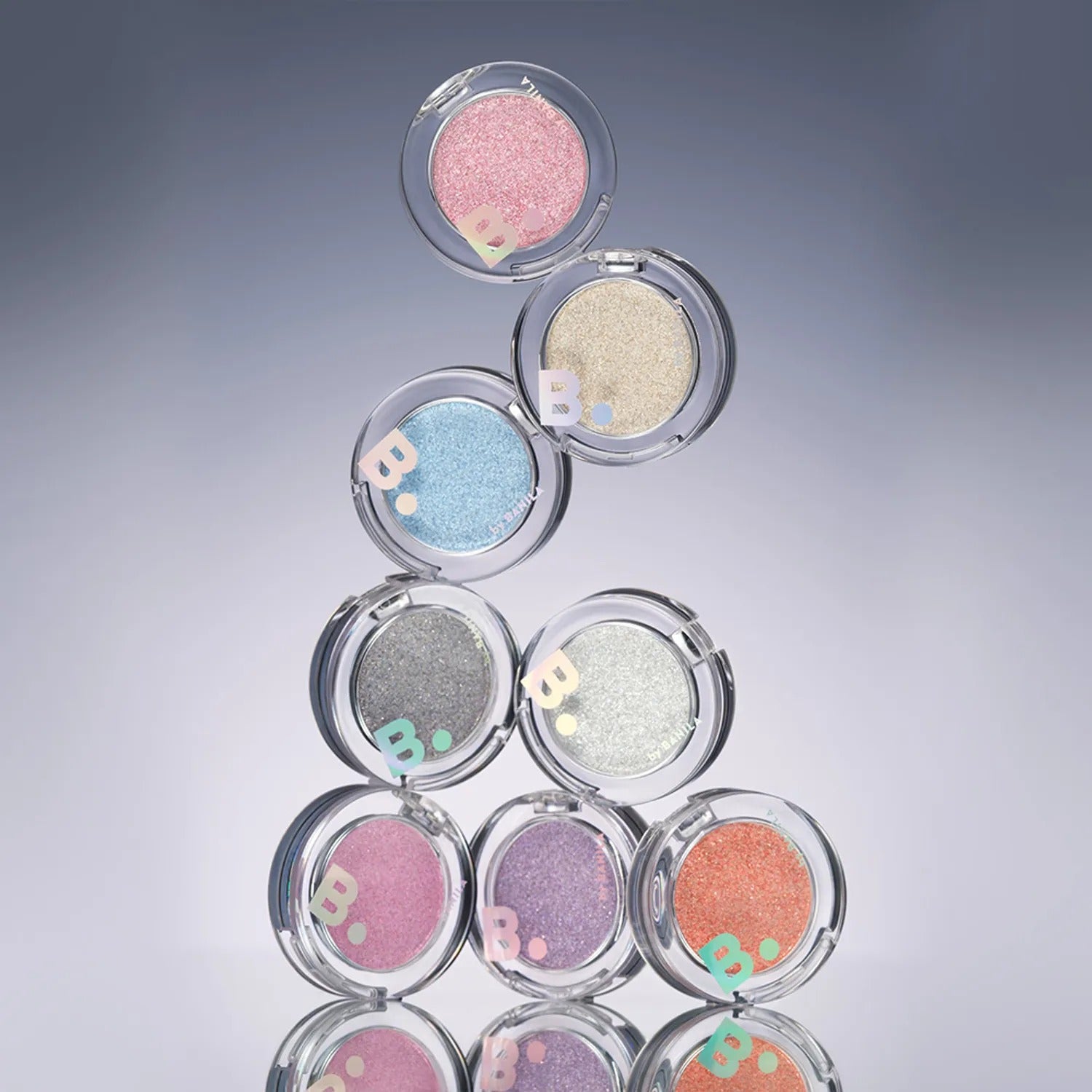 BANILA CO Hyper Holobeam Eye Glitter, maquillage yeux en fards scintillants roses, dorés et bleus sur fond bleu.