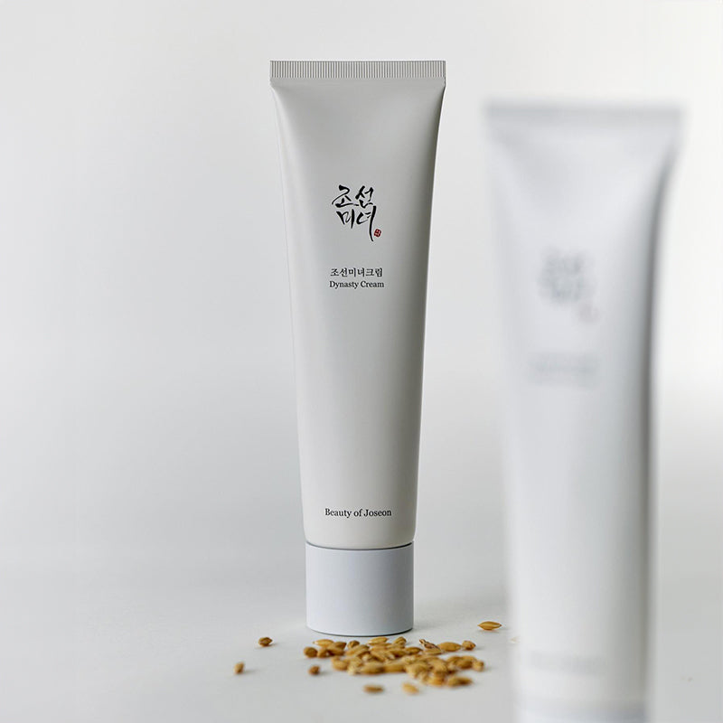 BEAUTY OF JOSEON Dynasty Cream 100ml, tube crème de la marque, posée sur fond blanc avec flocons de céréales.