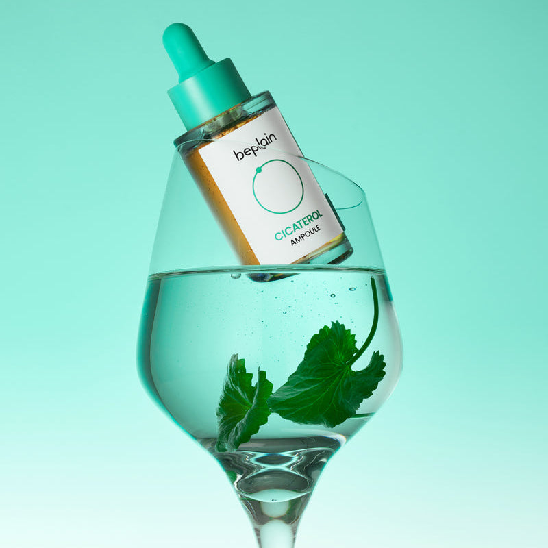 BEPLAIN Cicaterol Ampoule 30ml, sérum beplain posé dans un verre sur fond turquoise, flacon et sérum visibles