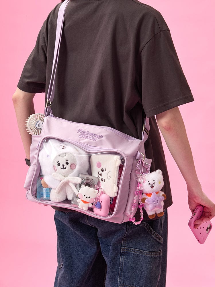 BT21 CLEAR POCKET MULTI CROSSBODY BAG THE JOURNEY, sac bandoulière violet transparent avec charms personnages sur fond rose.