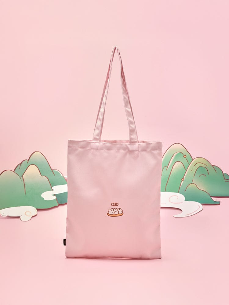 BT21 ECO BAG K-TOKKI, sac éco rose LINE FRIENDS avec K-Tokki, pochettes BT21, décor pastel devant un paysage.