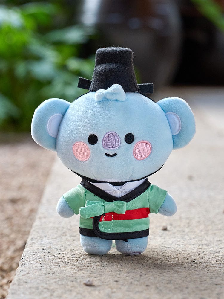 BT21 KOYA BABY PLUSH DOLL K-EDITION 2 : peluche koala douce, officielle LINE, en tenue verte, sur fond extérieur flou.