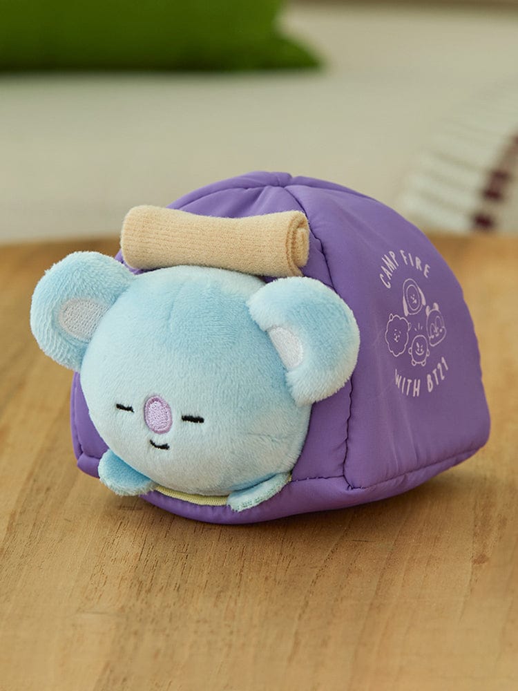 BT21 KOYA DOLL CAMPFIRE : peluche officielle LINE FRIENDS représentant KOYA au coin du feu, décor chambre, vue sur sol.