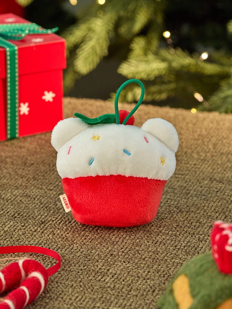 BT21 KOYA mini minini ORNAMENT PLUSH KEYRING PETITE HOLIDAY, porte-clés KOYA sur tapis, décor Noël vert et rouge en arrière-plan.