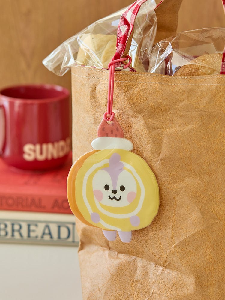 BT21 MANG BABY PVC NAME TAG BAKERY SHOP, porte-nom officiel LINE FRIENDS, sur sac en papier beige, ambiance boulangerie