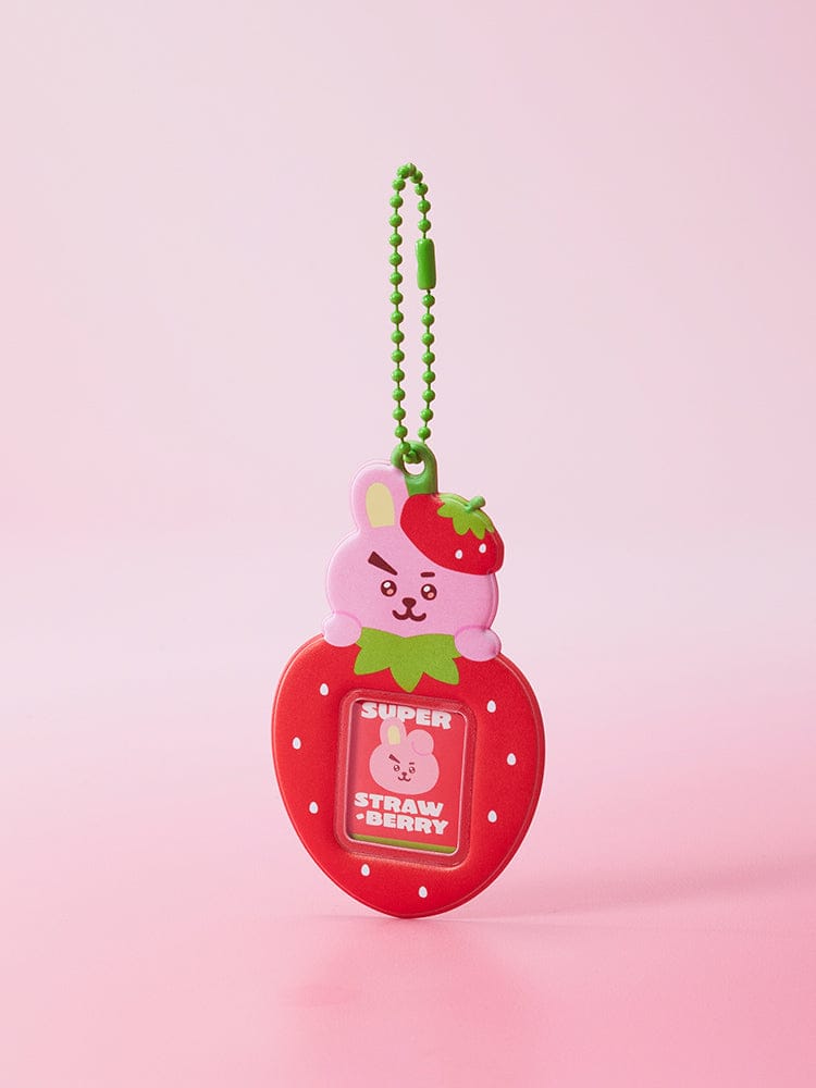 BT21 MINI PHOTO HOLDER KEYRING STRAWBERRY PARTY, porte-clés officiel BT21, pendentif fraise rouge sur fond rose pastel.