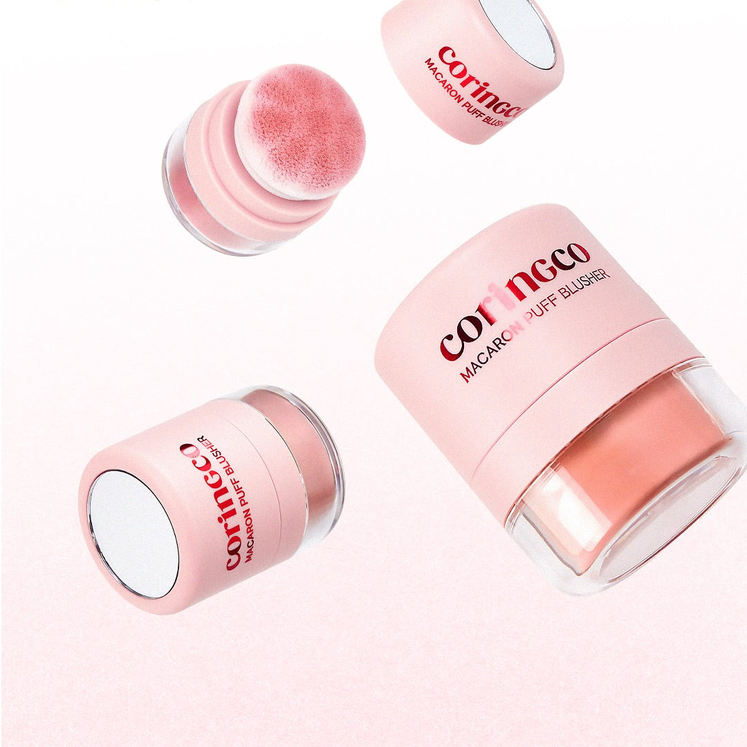 Décris l'image en français : CORINGCO Macaron Puff Blusher, produits CORINGCO rose maquillage, poudres et bouchon sur fond clair.