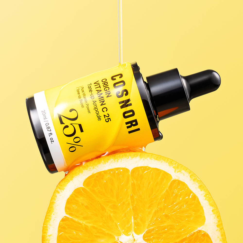 COSNORI Origin Vitamin C 25 Tone-Up Ampoule 20ml, flacon jaune sur fond jaune, avec tranche d’orange et gouttes de sérum