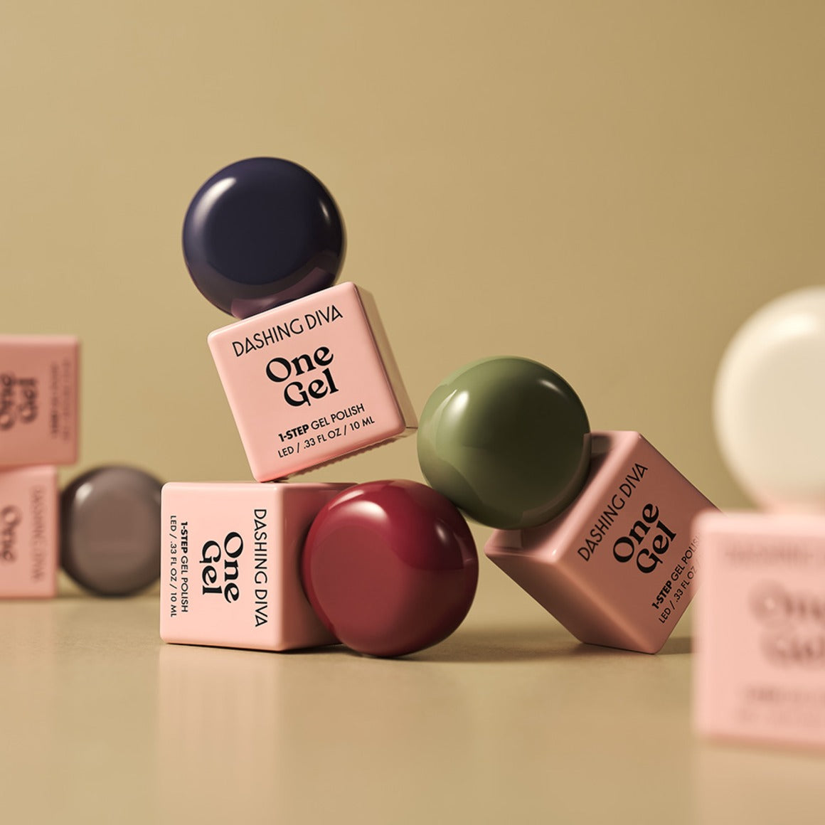 DASHING DIVA Wonzel Autumn Depths : flacons One Gel aux tons automnaux, sur fond beige avec autres teintes de la marque.
