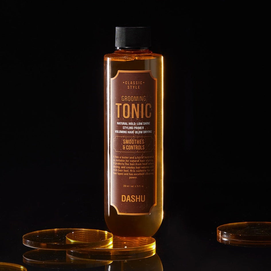 DASHU Classic Style Grooming Tonic 200ml de la marque DASHU, flacon ambré sur fond noir avec gouttes d’huile.