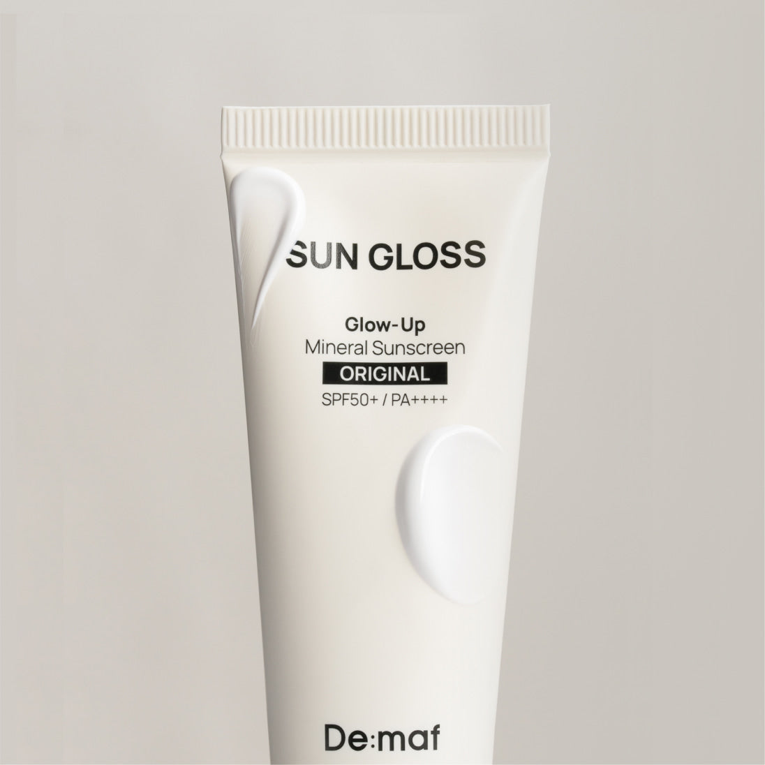 DE:MAF Sun Gloss Glow Up Inorganic Sunscreen 50ml Original, tube blanc sur fond clair, marque De:mof, écran solaire minéral SPF.