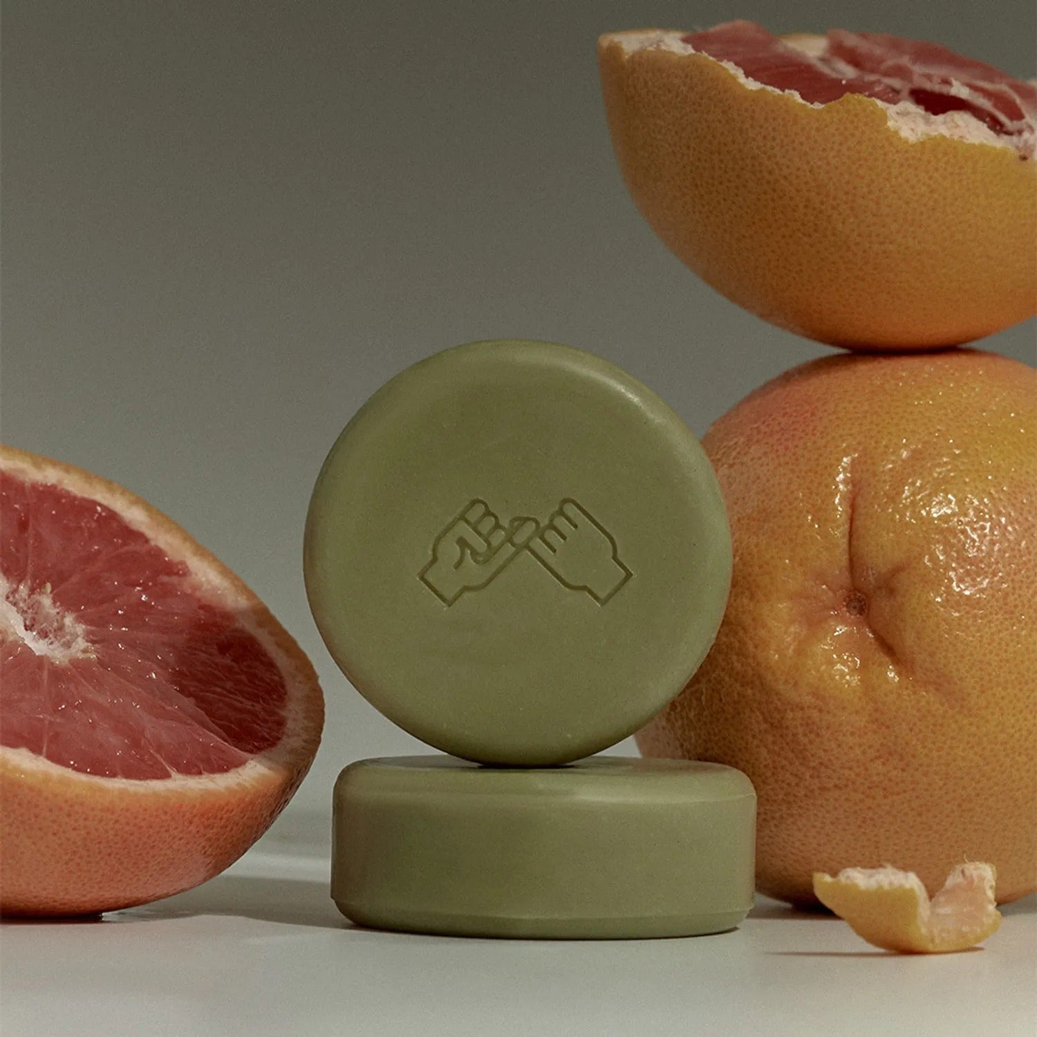 DONGGUBAT Correct Shampoo Bar For Dry Skin, savon solide présenté sur fond neutre, agrumes en arrière-plan.