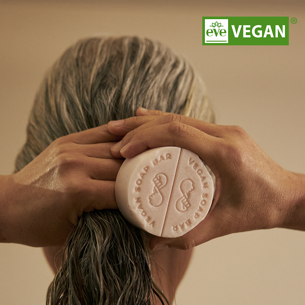 Décrivez l'image : DONGGUBAT Vegan Treatment Bar Dongbaek de la marque DONGGUBAT, main tenant un savon sur fond beige.