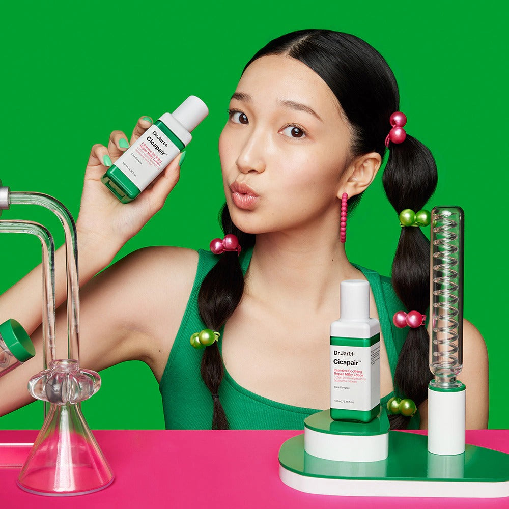 Femme posant avec DR.JART+ Cicapair Intensive Soothing Repair Milky Lotion 100ml devant un fond vert, image promotionnelle.
