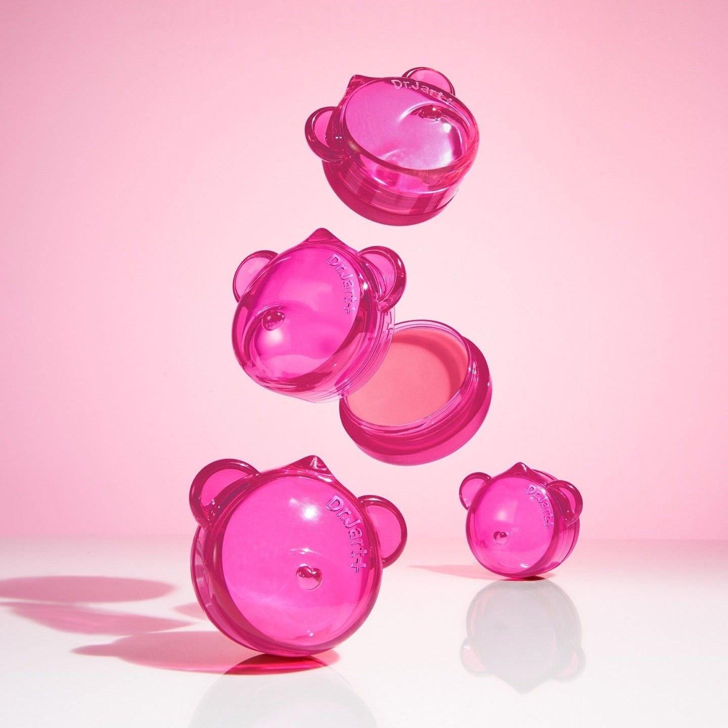 DR.JART+ Vital Hydra Solution™ Hydrating Lip Mask sur fond rose, quatre boîtes roses de masque pour les lèvres en suspension.