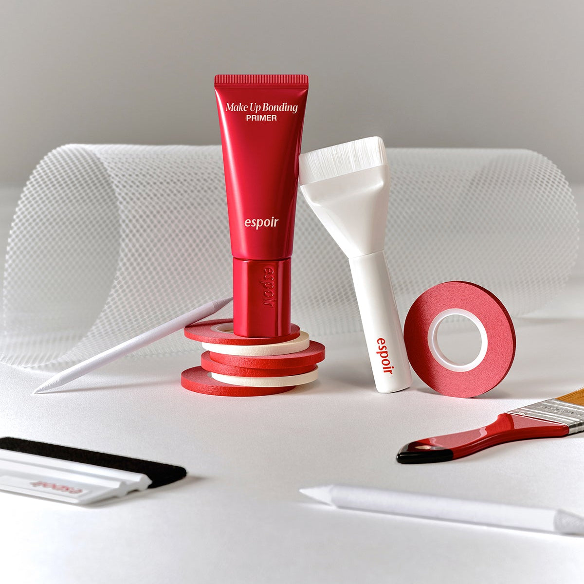 ESPOIR Make Up Bonding Primer rouge espoir sur fond maquillage, avec outils et ruban rouge, style studio