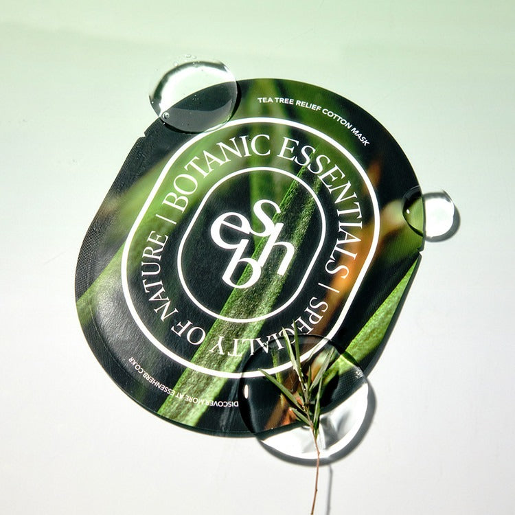 Masque en coton ESSENHERB Tea Tree Relief 5EA posé sur une surface avec des gouttes d'eau, apaisement cutané naturel.
