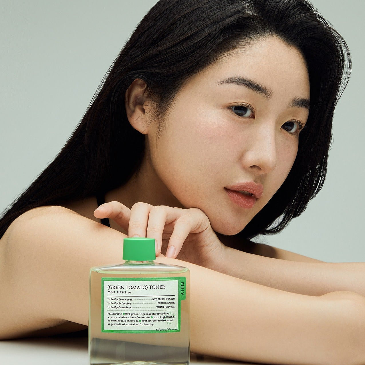 Femme posant avec FULLY Green Tomato Toner 250ml, cosmétique naturel pour soin de la peau.