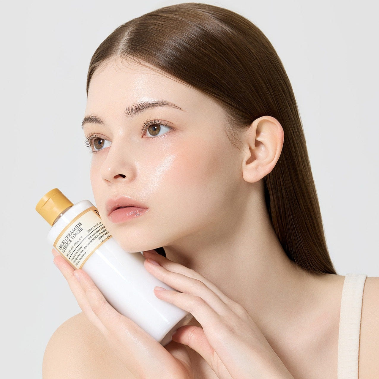 Modèle tenant le FULLY Rice Serum Essence Toner 250ml pour un soin de la peau élégant et raffiné.