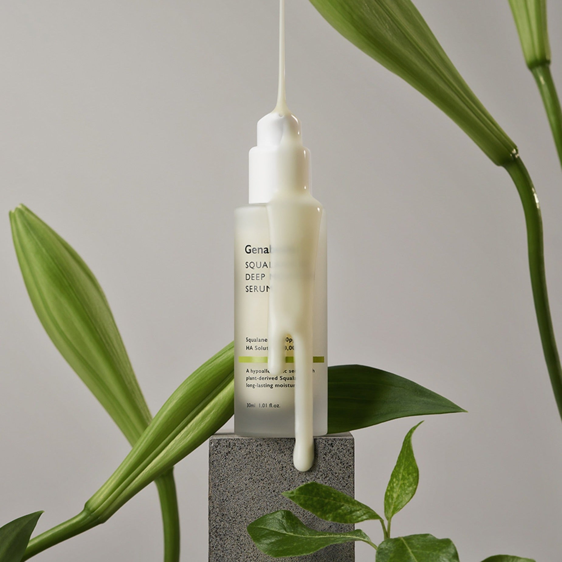 GENABELLE Squalane 53 Deep Moisture Serum 30ml en train de couler sur un bloc, entouré de feuilles vertes élégantes.