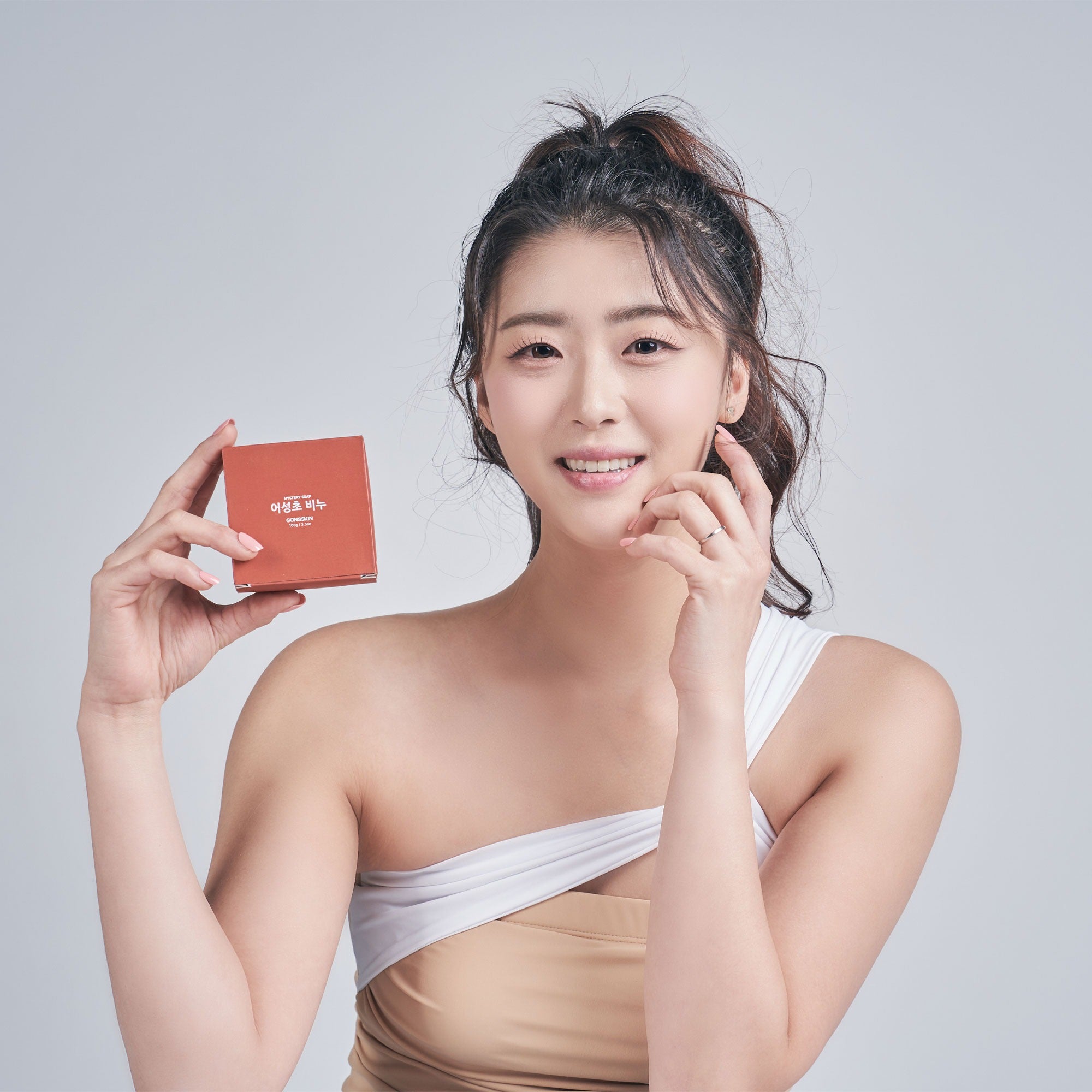 Femme tenant GONGSKIN Eoseongcho Soap 100g avec sourire.