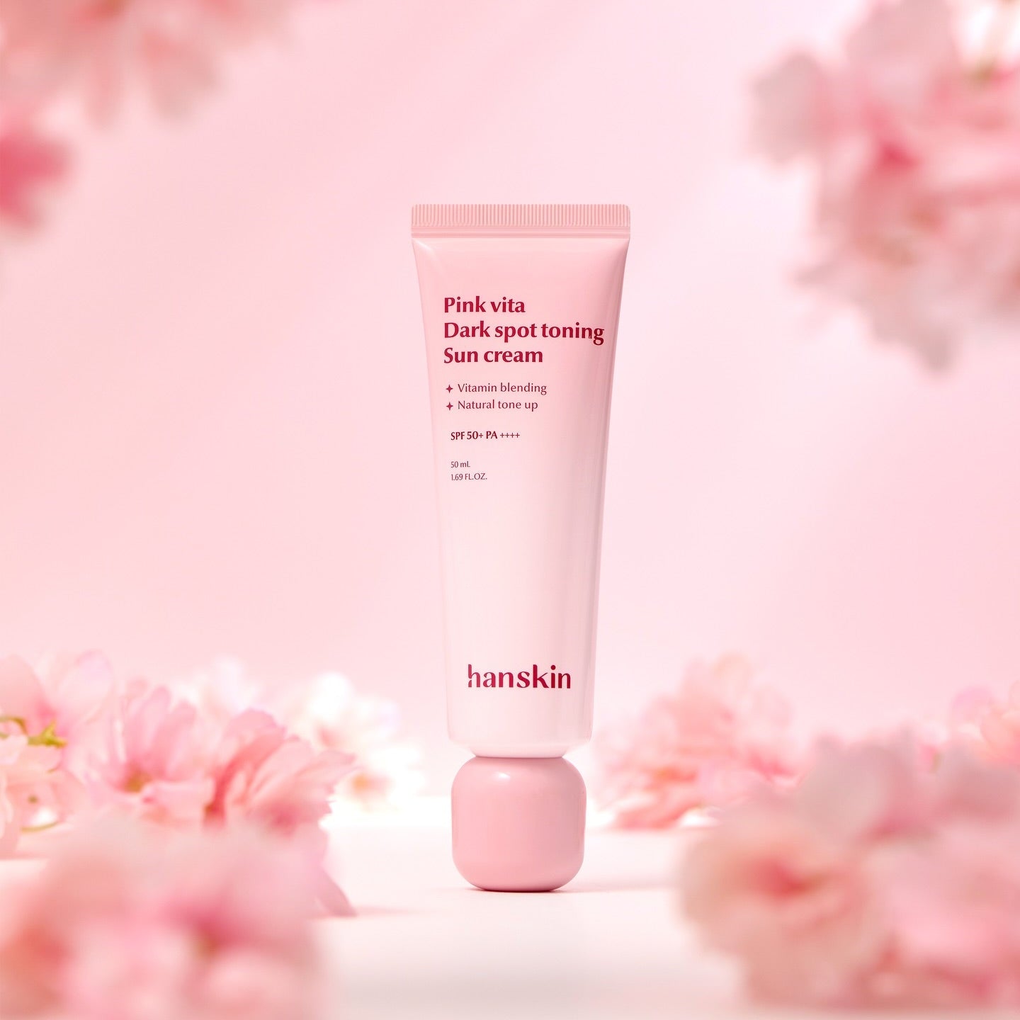 HANSKIN Pink Vita Blemish Toning Sun Cream 50ml, tube rose sur fond floral rose, marque HANSKIN en contexte beauté