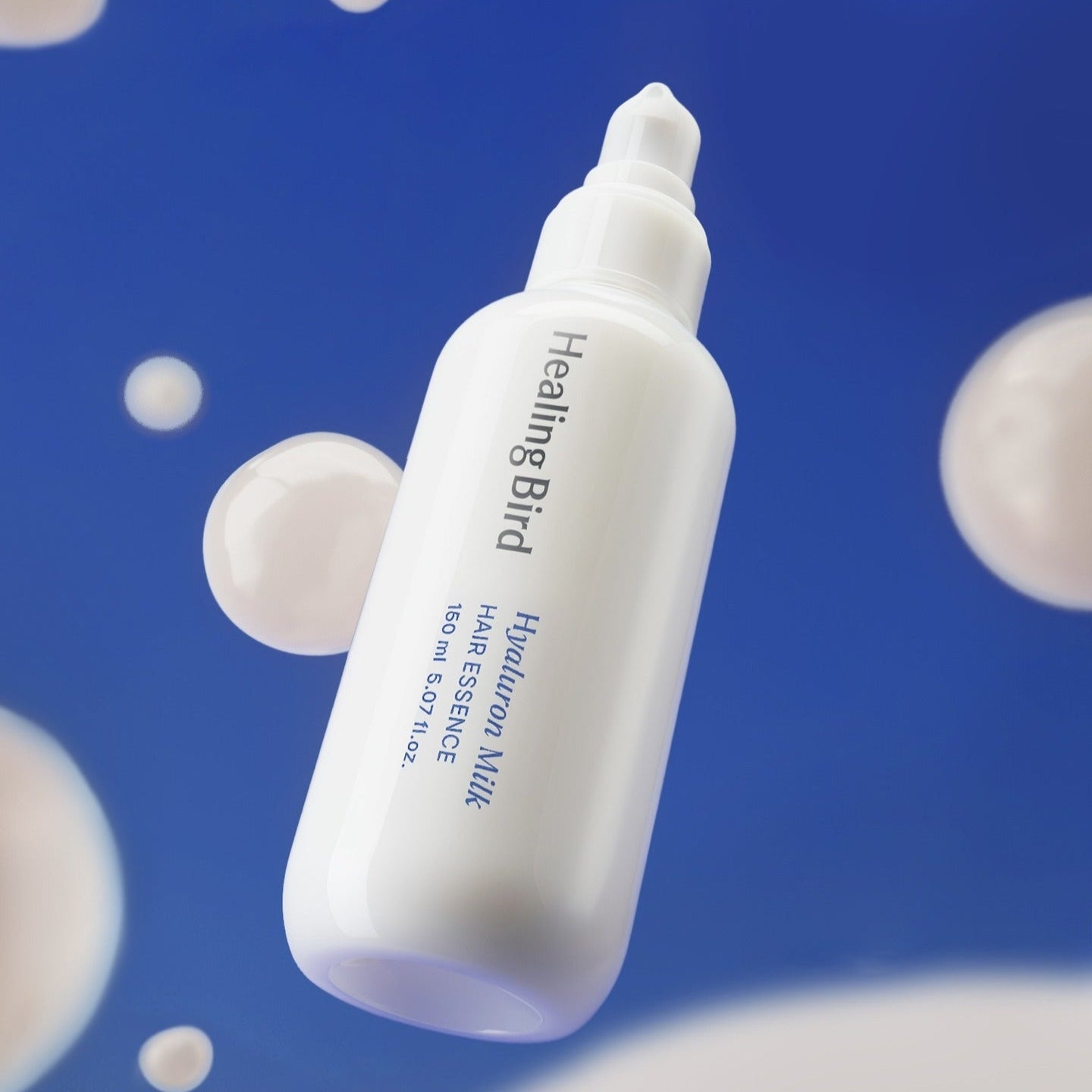 HEALING BIRD Hyaluronic Milk Hair Essence 150ml, flacon blanc sur fond bleu, gouttes et bulles, produit marque visible