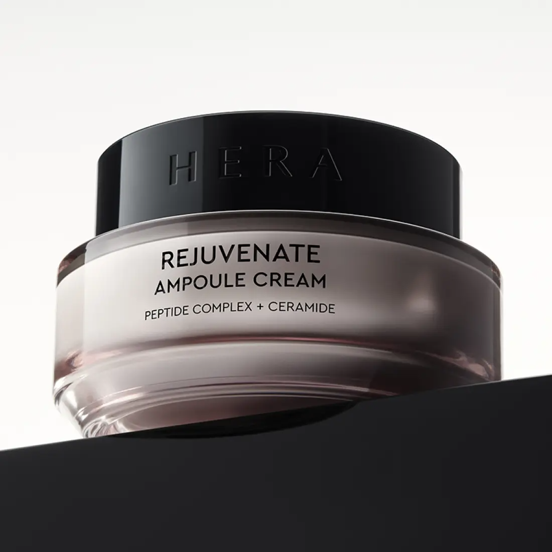 HERA Rejuvanate Ampoule Cream 50ml en pot élégant reposant sur une surface noire, mettant en valeur la marque et le design luxueux.