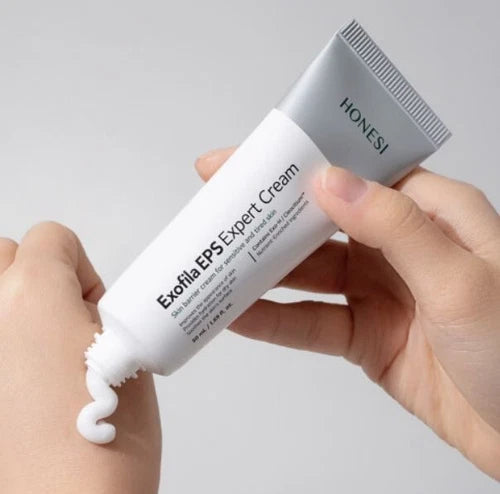 Décrivez l’image : HONESI Exophila EPS Expert Cream 50ml, tube cosmétique et crème blanche appliquée sur peau, mains en gros plan.