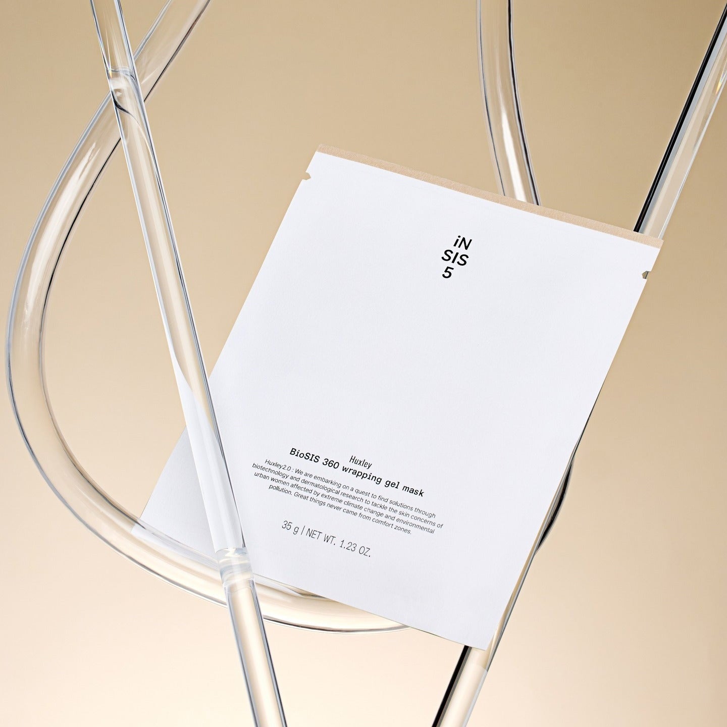 Masque en gel HUXLEY BioSIS 360 Wrapping 35g sur une chaise transparente.