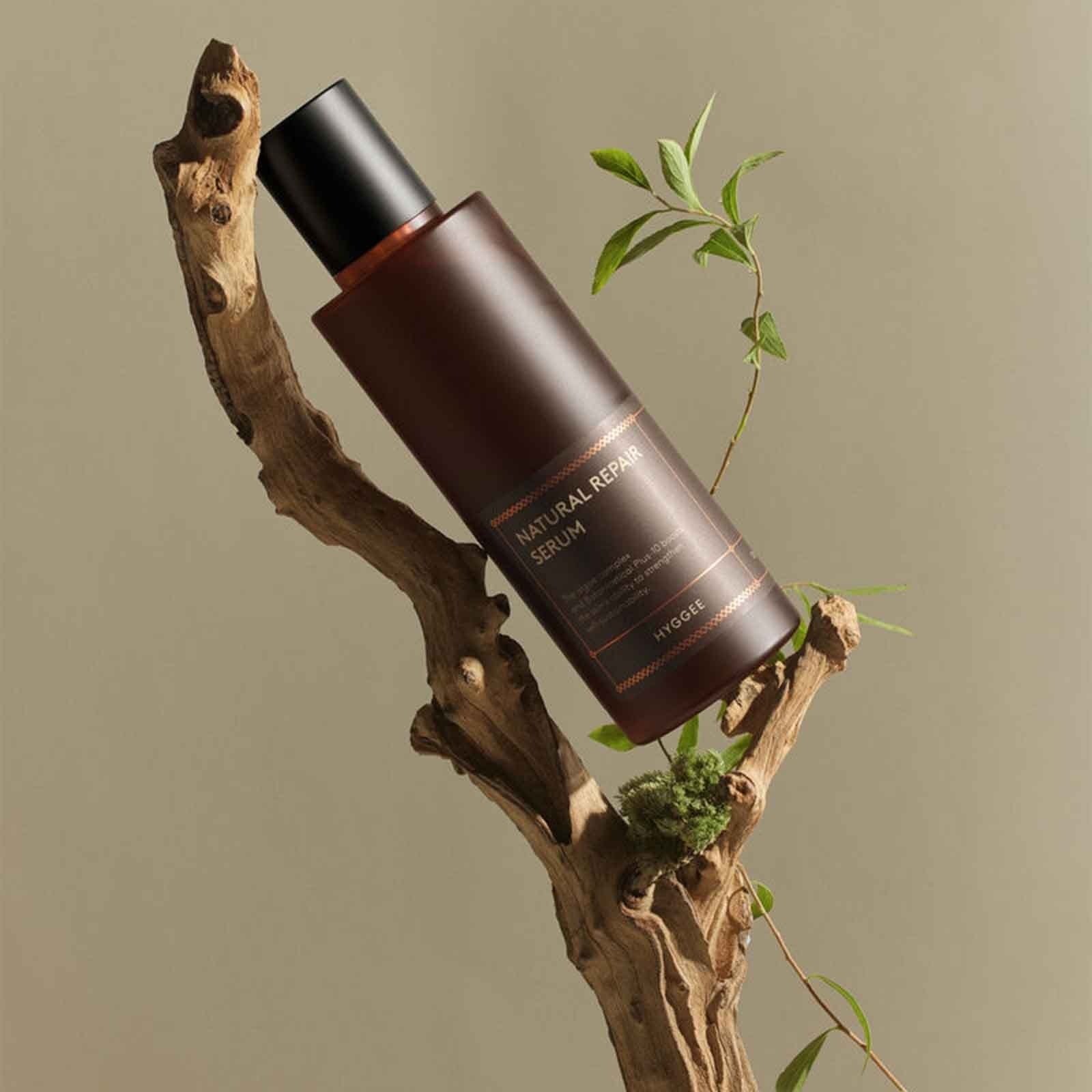 HYGGEE Natural Repair Serum 120ml, flacon sur branche naturelle avec feuilles et ambiance soin, marque HYGGEE