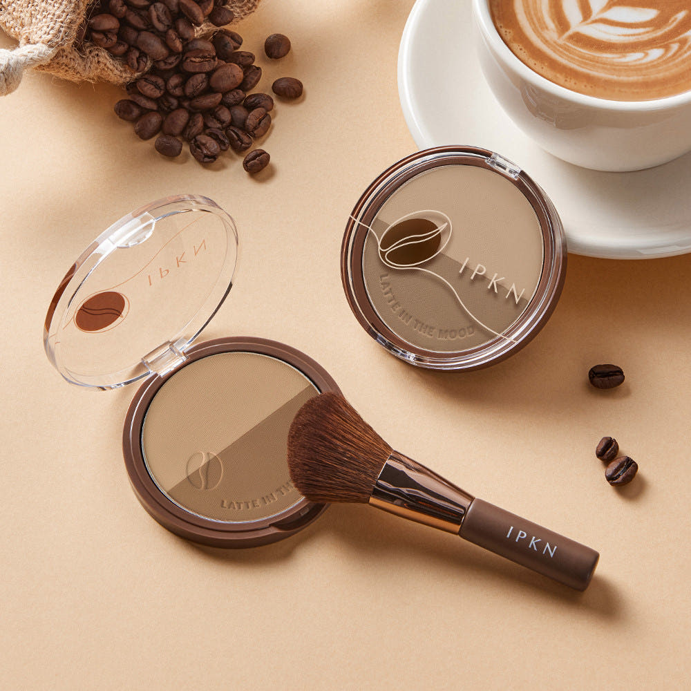 IPKN Latte in the Mood Contouring de la marque IPKN, poudre et pinceau, scène café avec grains de café.