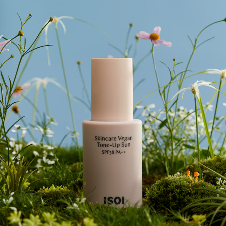 ISOL Skincare Vegan Tone-Up Sun SPF38, PA++ 40ml dans l’herbe, flacons ISOI et fleurs au soleil (photo produit)