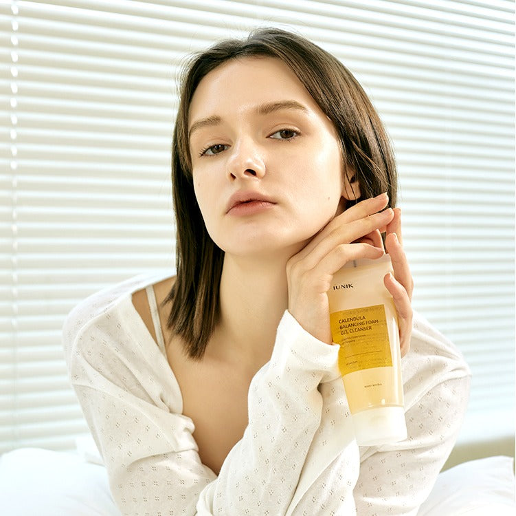 Femme tenant IUNIK Calendula Balancing Foam Gel Cleanser 150ml, démonstration de soin de la peau équilibrant avec calendula.