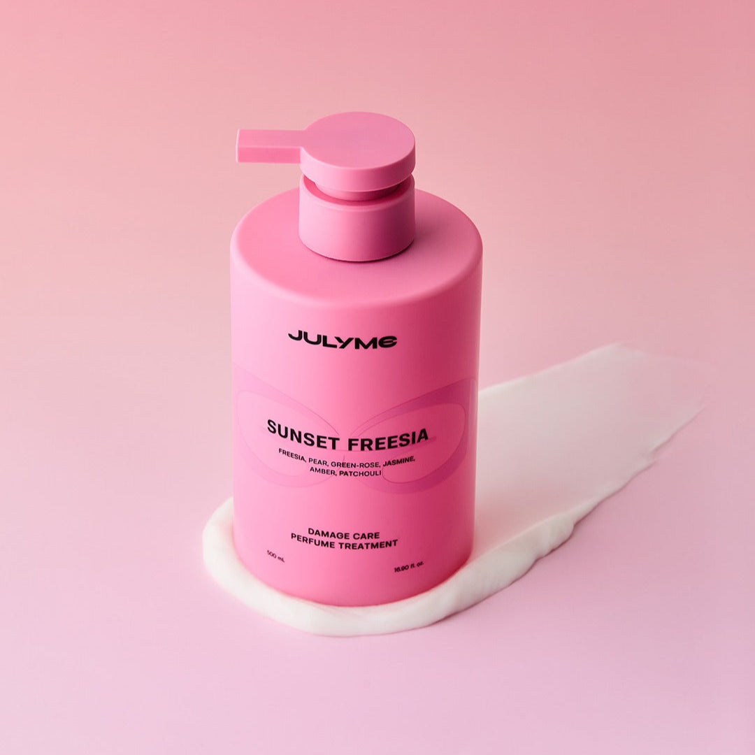 JULYME Damage Care Perfume Hair Treatment 500ml de la marque JULYME, flacon rose sur fond rose, contexte soin capillaire.