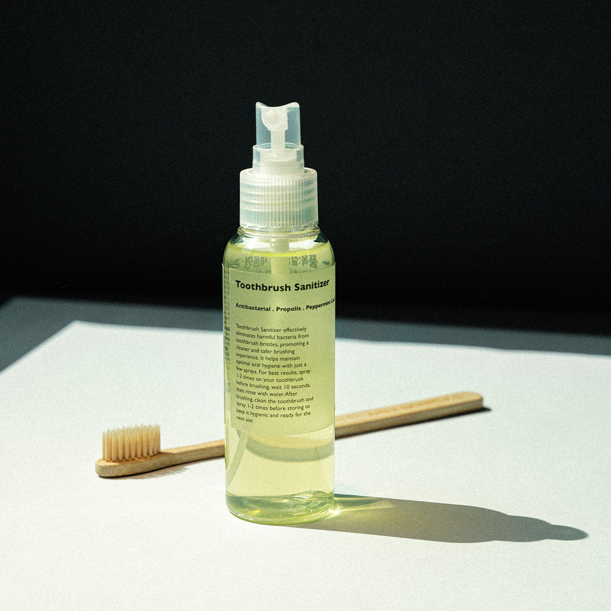 LAZY SOCIETY Toothbrush Sanitizer 100ml, flacon avec pompe sur fond noir, brosse à dents en contexte d’hygiène