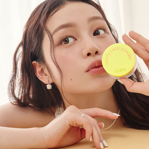 LUNA Comfy Clear Powder de la marque LUNA, maquillage en poudre sur une femme tenant le produit, fond clair.